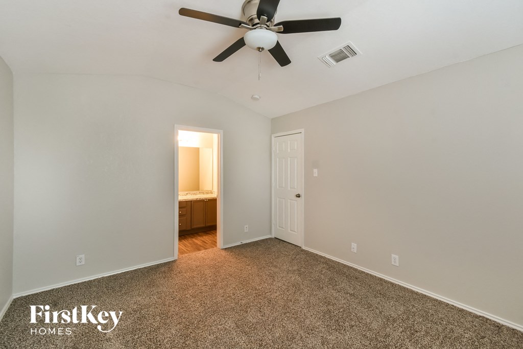 a bedroom with a ceiling fan and a door to a bathroom