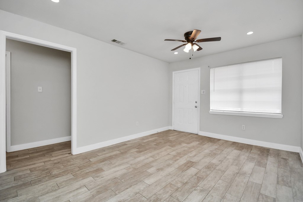 A room with a ceiling fan and a window with blinds.