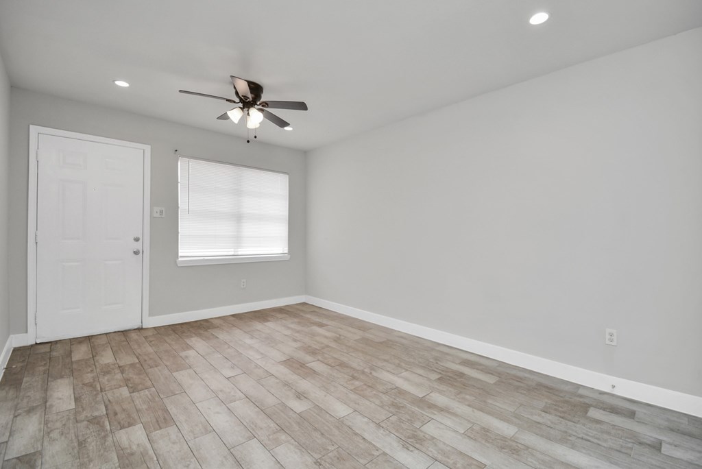 A room with a ceiling fan and a door.