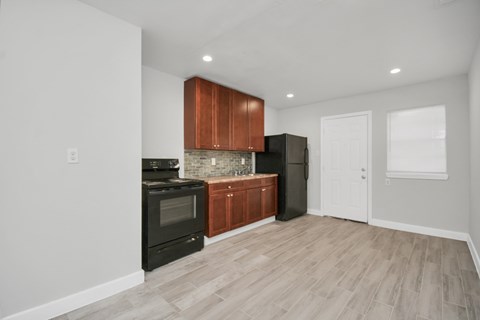 A kitchen with a black oven and brown cabinets.