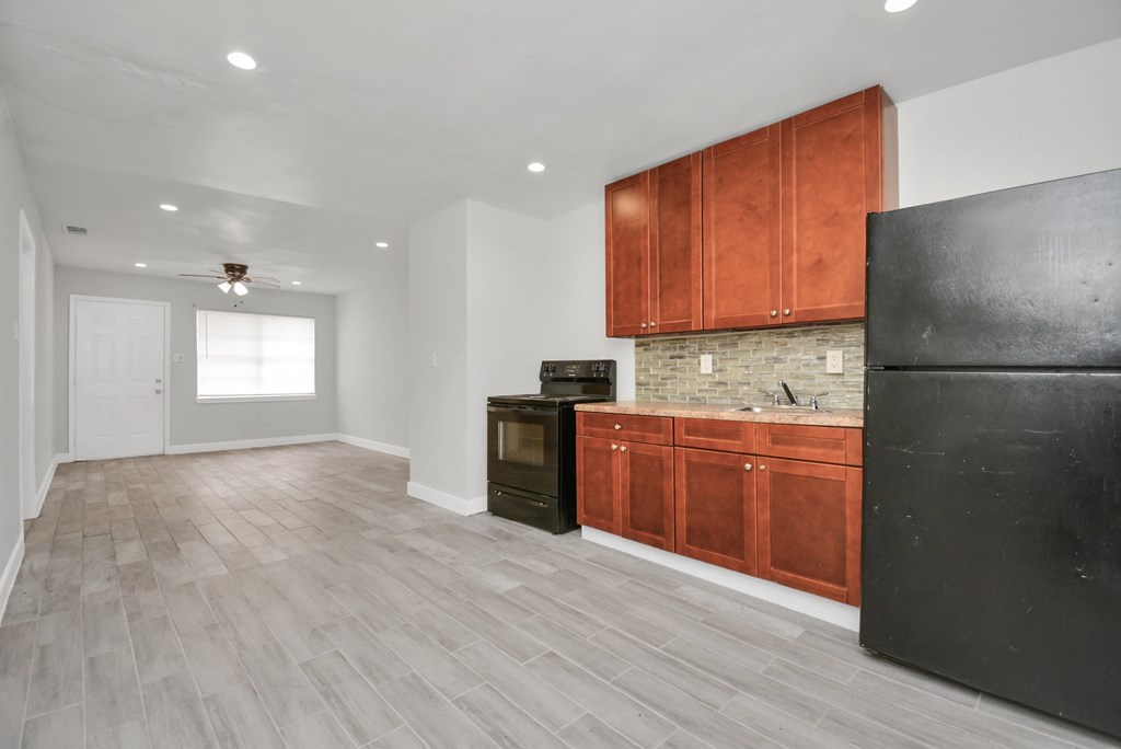 A kitchen with wooden cabinets and a black refrigerator.