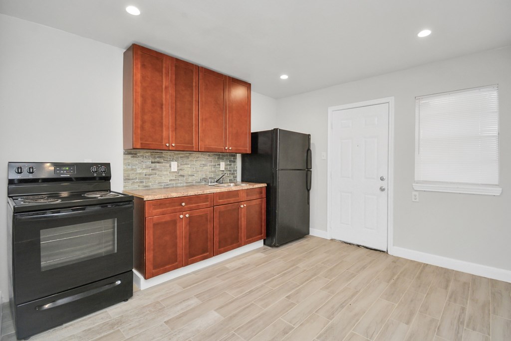 A kitchen with wooden cabinets and a black refrigerator.
