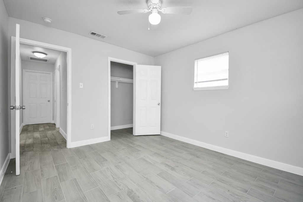 A room with a white door, a window, and a ceiling fan.