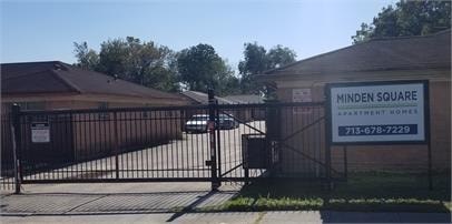 A gated entrance to a property with a sign that says Minden Square Apartment Homes.
