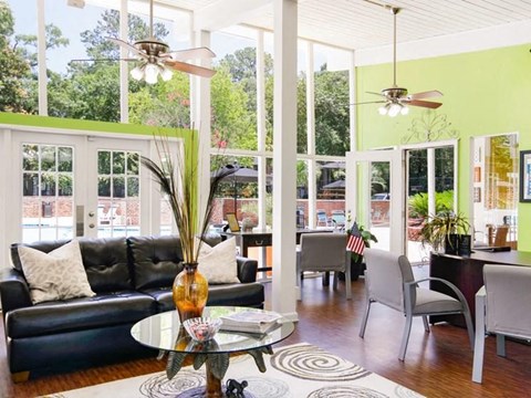a living room with a black leather couch and a glass table