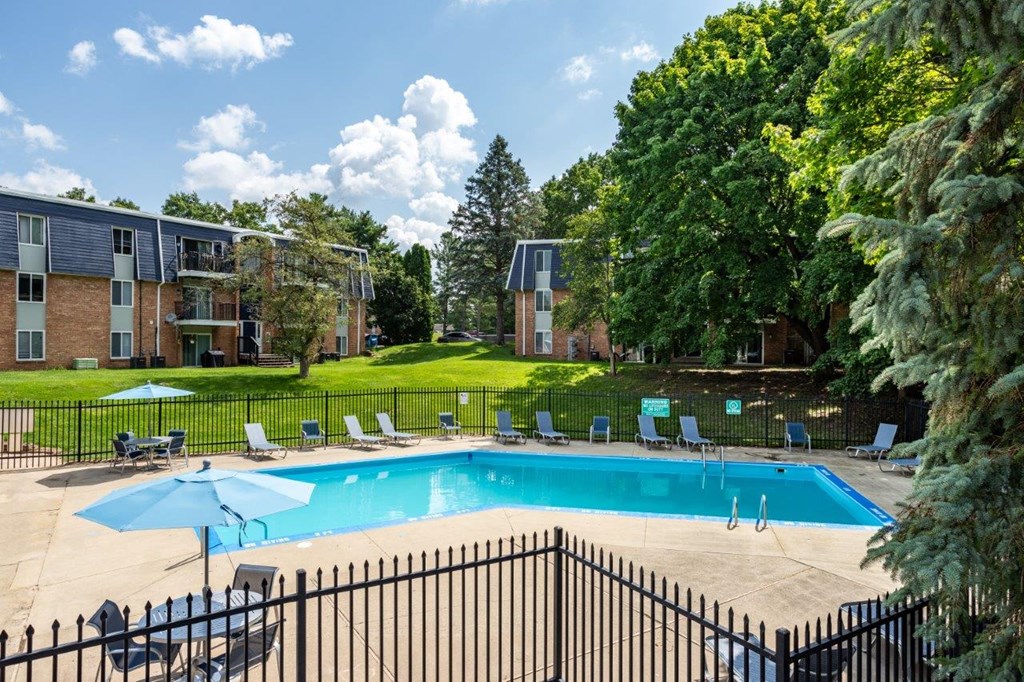 A black fence surrounds a small pool with lounge chairs.