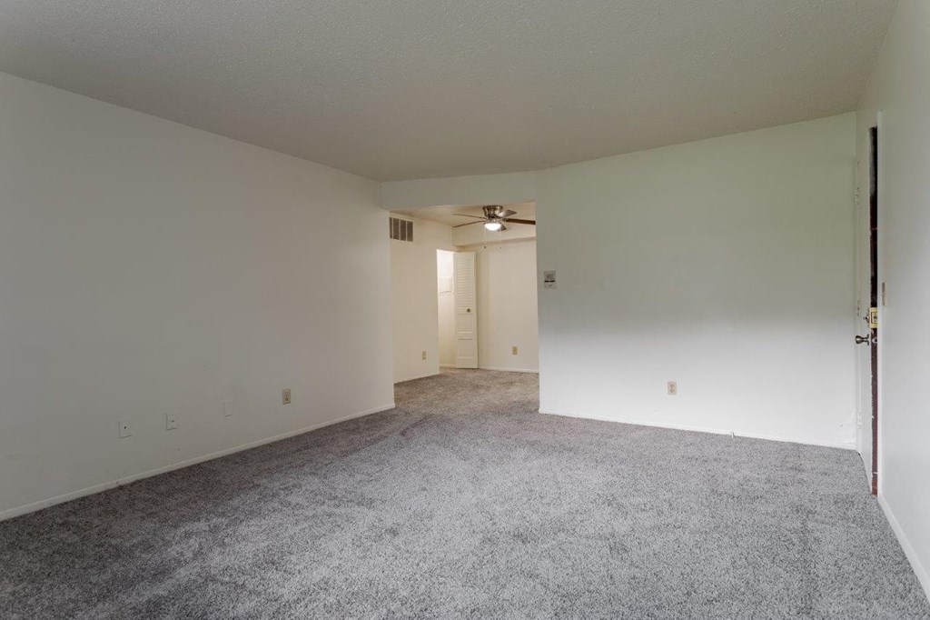 A room with a carpeted floor and a ceiling fan.