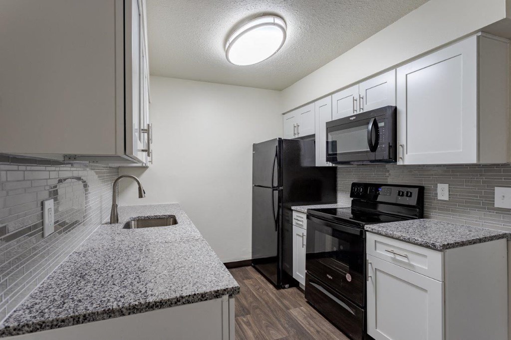 A kitchen with black appliances and a granite countertop.