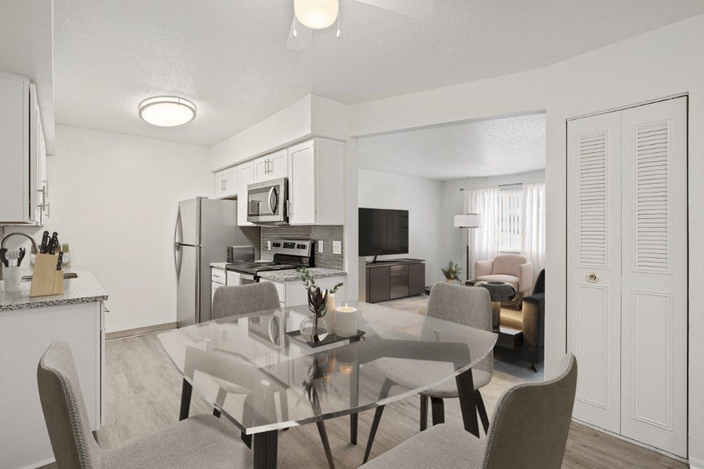 A modern kitchen with a glass dining table and chairs.