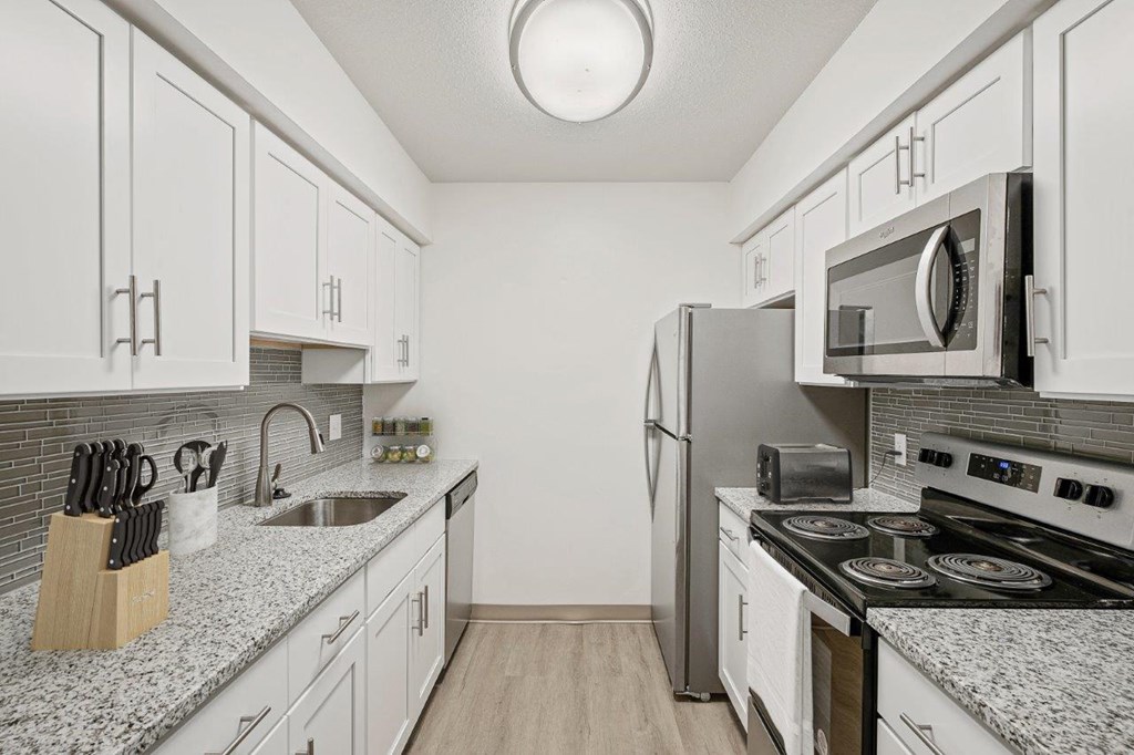A kitchen with white cabinets and a granite countertop.