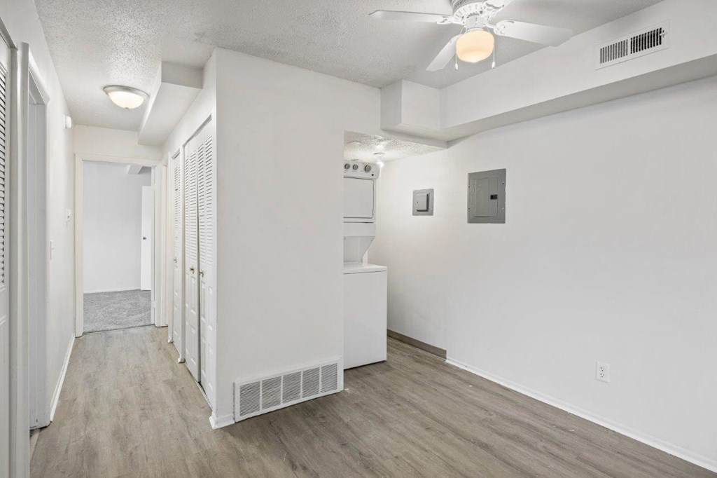 A long hallway with a white wall and a white door.