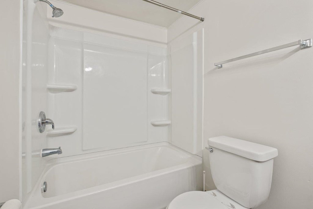 A white bathroom with a toilet, tub, and shower.