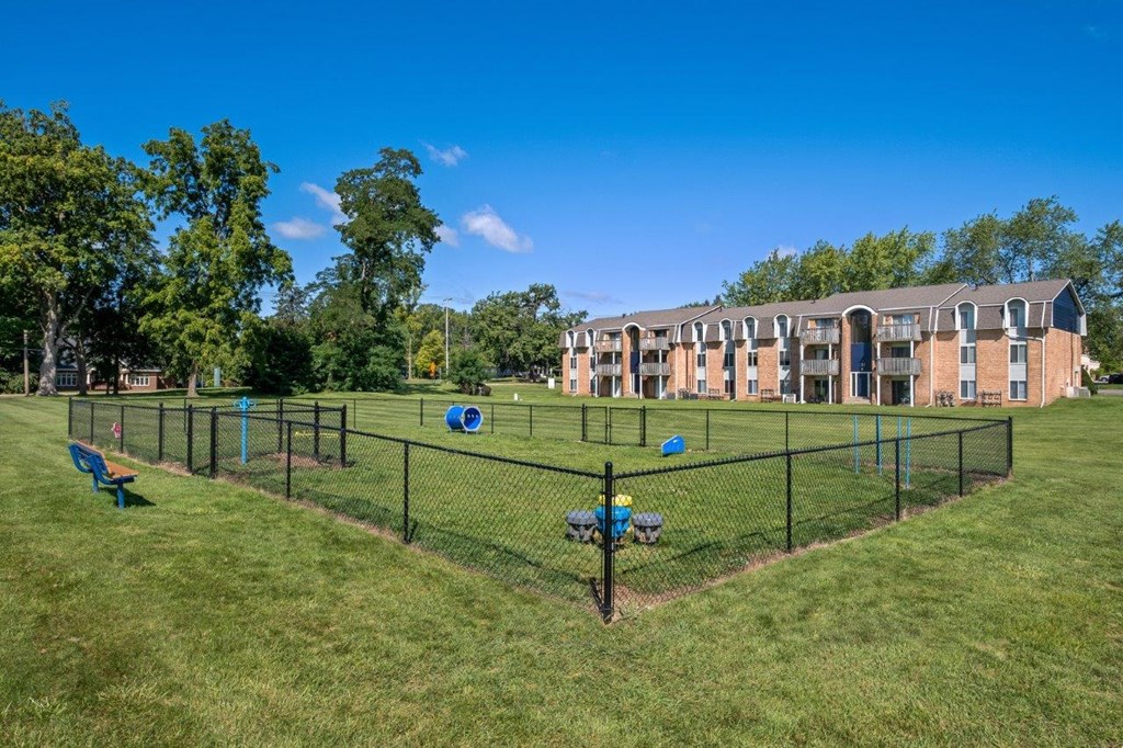 A park with a fence, a blue tarp, and a green lawn.