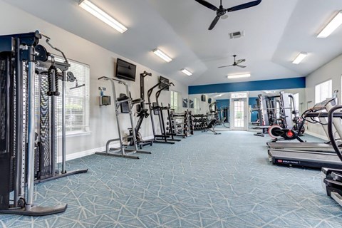 a gym with weights and cardio equipment on the floor and a window