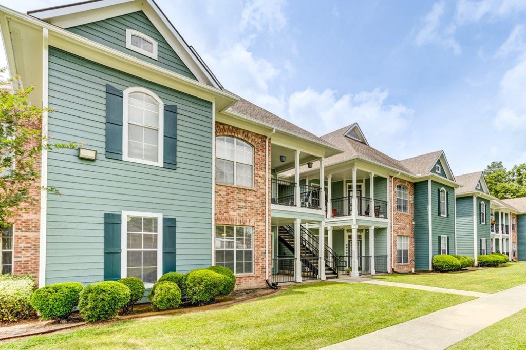 the outlook of a row of town homes with green siding and brick