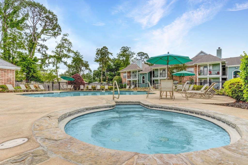 a large pool with chairs and umbrellas in front of a house