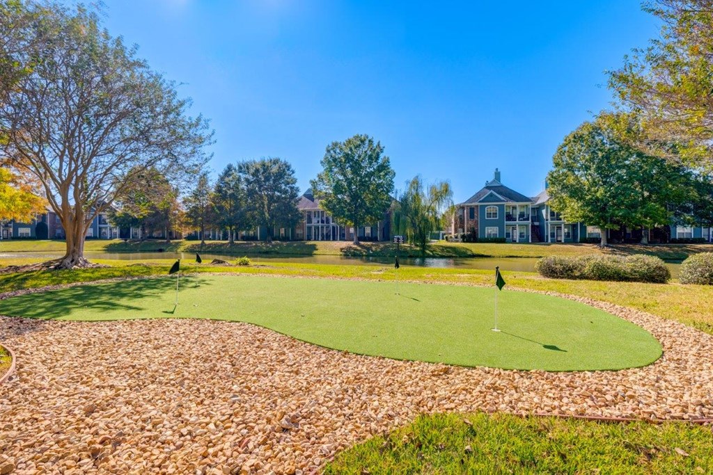 a putting green with a house in the background