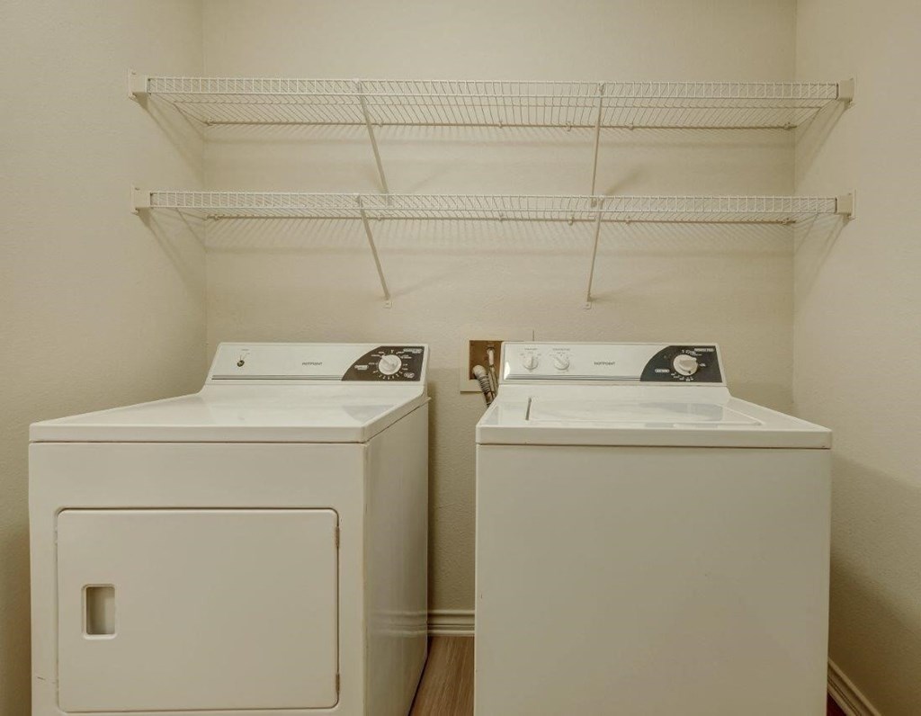 two washers and dryers in a laundry room with a shelf above
