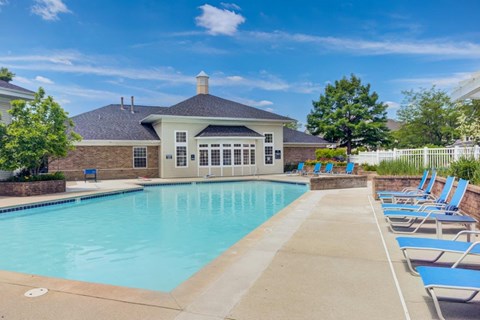 a pool with chairs and a house in the background