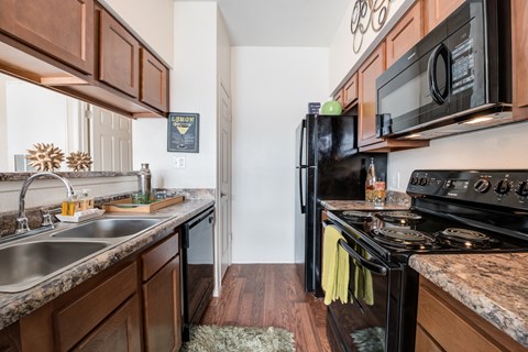 a kitchen with black appliances and wooden cabinets and a black stove top oven