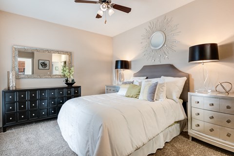 a bedroom with a large white bed and a sunburst mirror