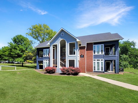 a blue house with a lawn and trees in front of it