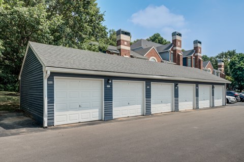 a garage with white garage doors and a house in the background