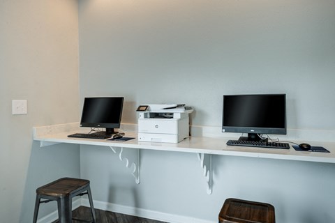 a computer desk with two monitors and a printer on it