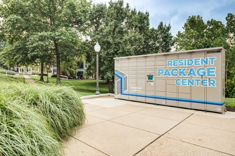 a building with a sign for the resident package center in front of trees and grass