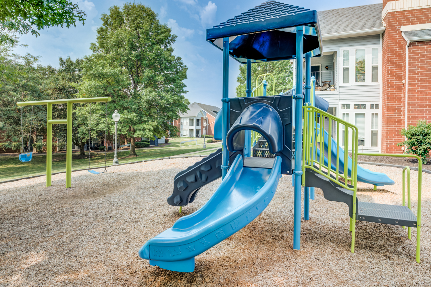 a playground with a blue slide at an apartment complex