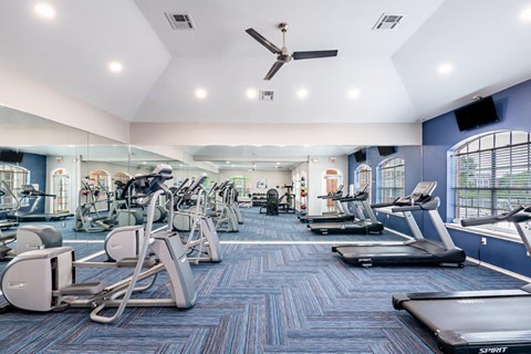 a gym with cardio equipment and weights on the floor