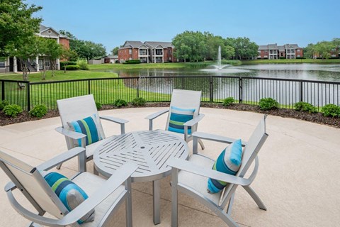 a patio with a table and chairs in front of a fountain