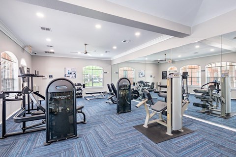 a gym with weights and cardio equipment in a building with windows