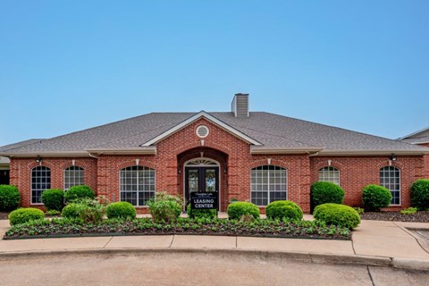 the front of a brick house with a driveway and landscaping