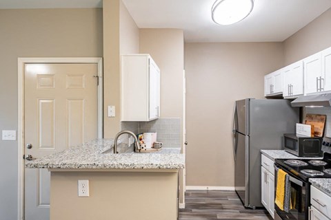 a kitchen with a granite counter top and a stainless steel refrigerator