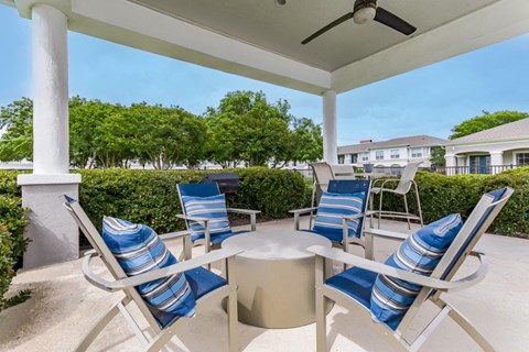 a patio with blue and white chairs and a table