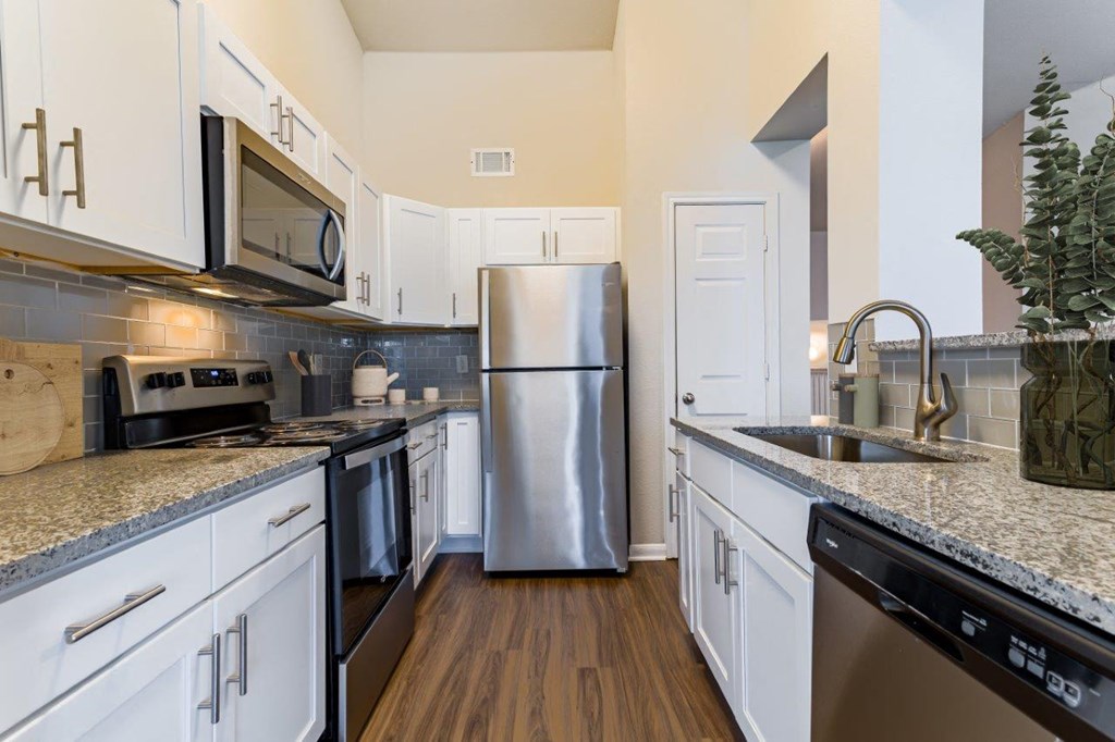 a kitchen with white cabinets and a stainless steel refrigerator