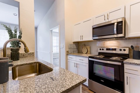a kitchen with granite counter tops and white cabinets