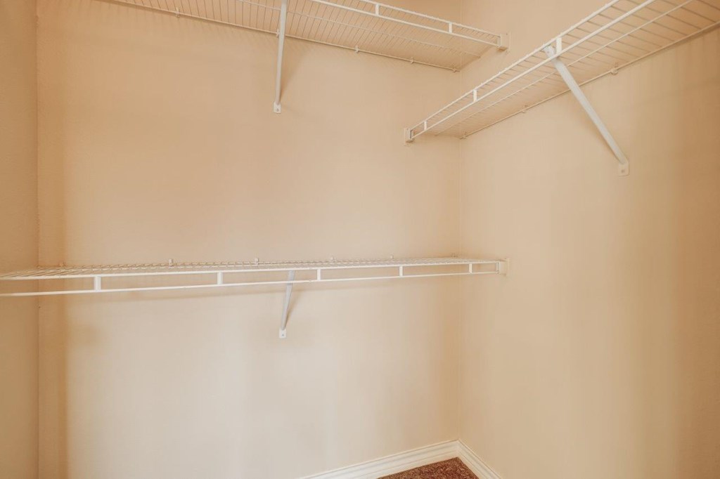 a walk in closet with shelves and hooks on the wall