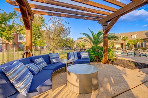 a patio with blue couches and tables and a wooden pergola