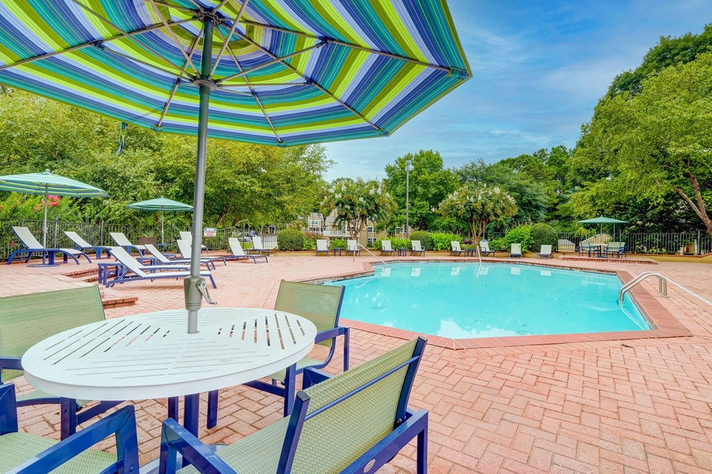 a swimming pool with a table and chairs under an umbrella