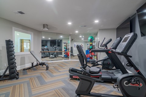 a gym with treadmills and other exercise equipment in a room with a mirror