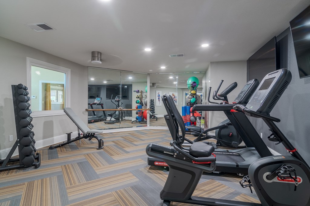 a gym with treadmills and other exercise equipment in a room with a mirror