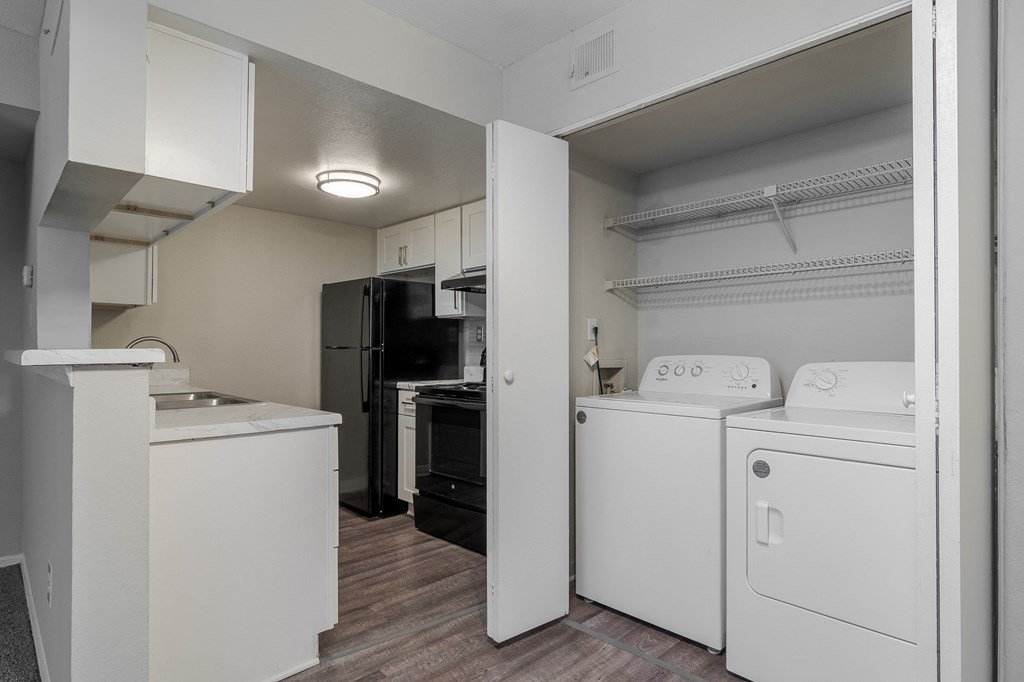a white laundry room with a washer and dryer and a black refrigerator