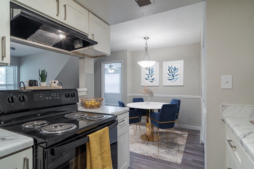 an open kitchen and dining room with black appliances and a table and chairs