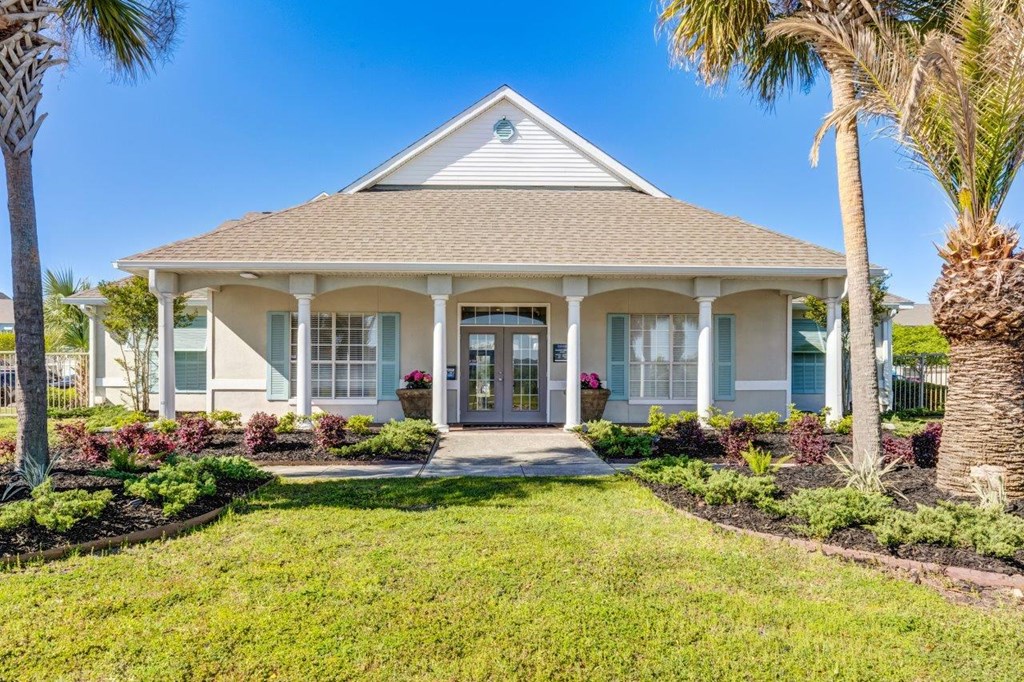 the front of a house with a lawn and palm trees