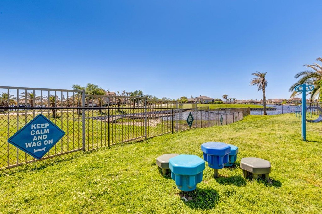a park with tables and stools in the grass near a fence