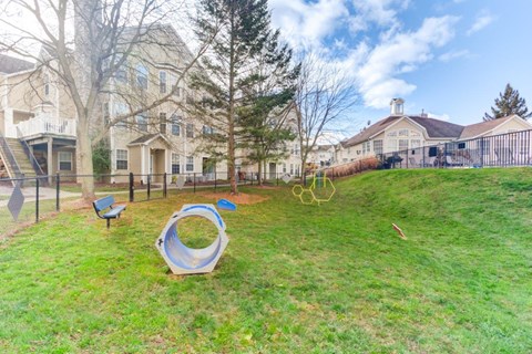 A playground with a slide and swings in a grassy area.