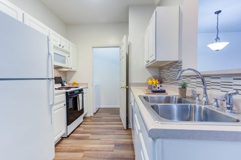 A kitchen with white appliances and wooden floors.