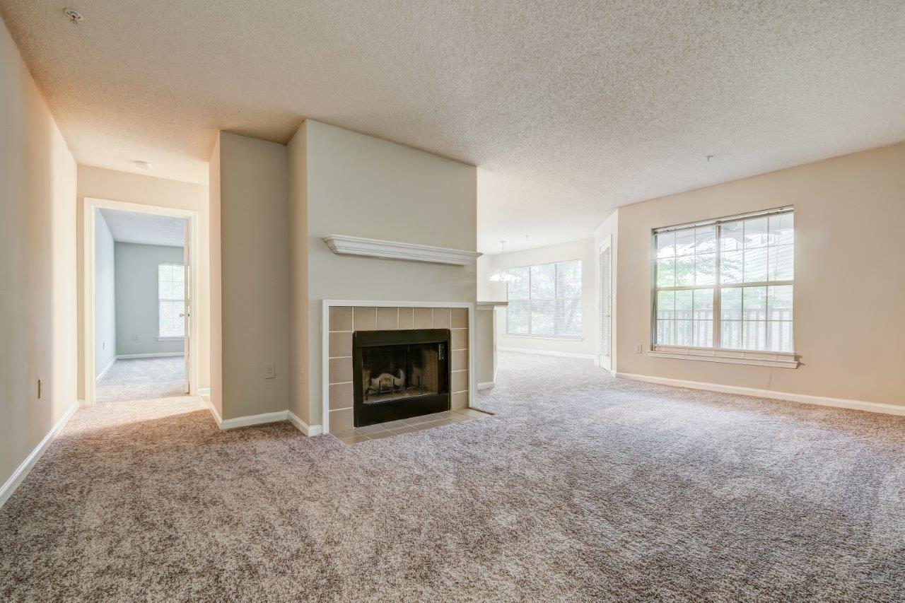 A living room with a fireplace and carpeted floor.